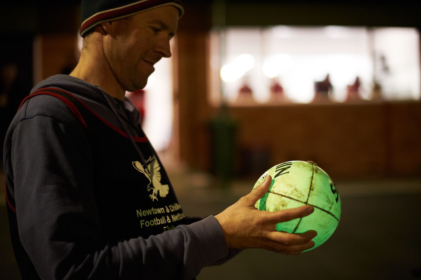 A club player holding a glowing green Chargeball at night training