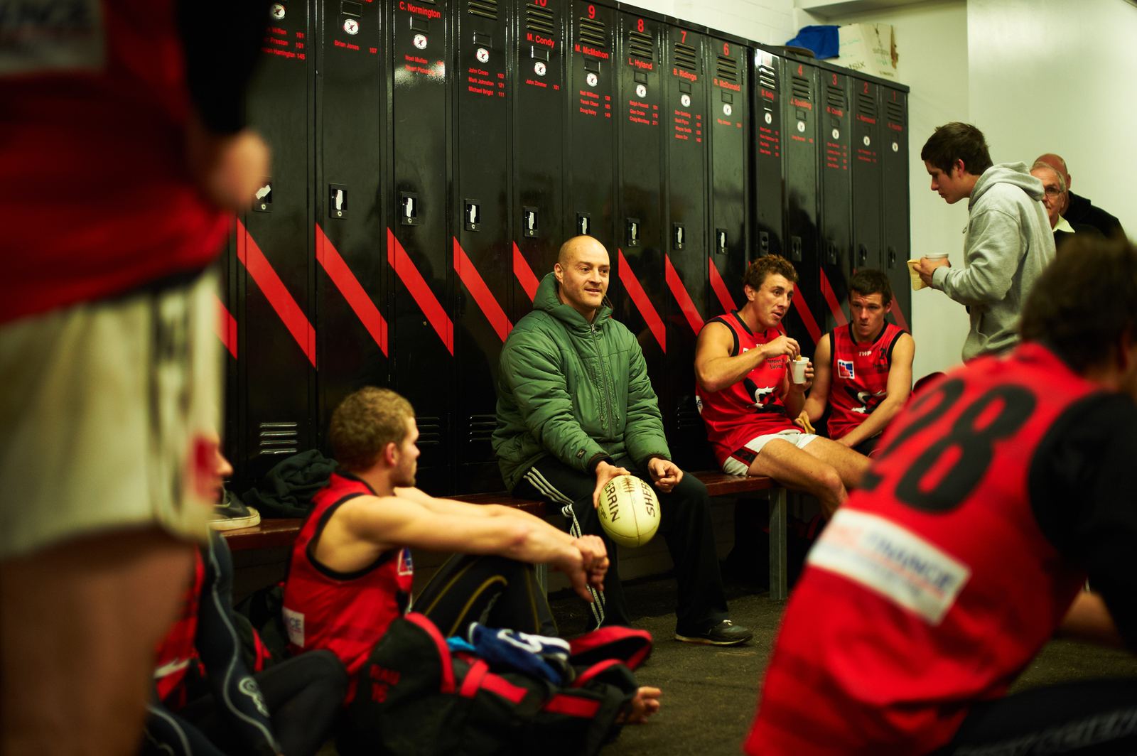 Football club players in the locker room after a match, one holding a football