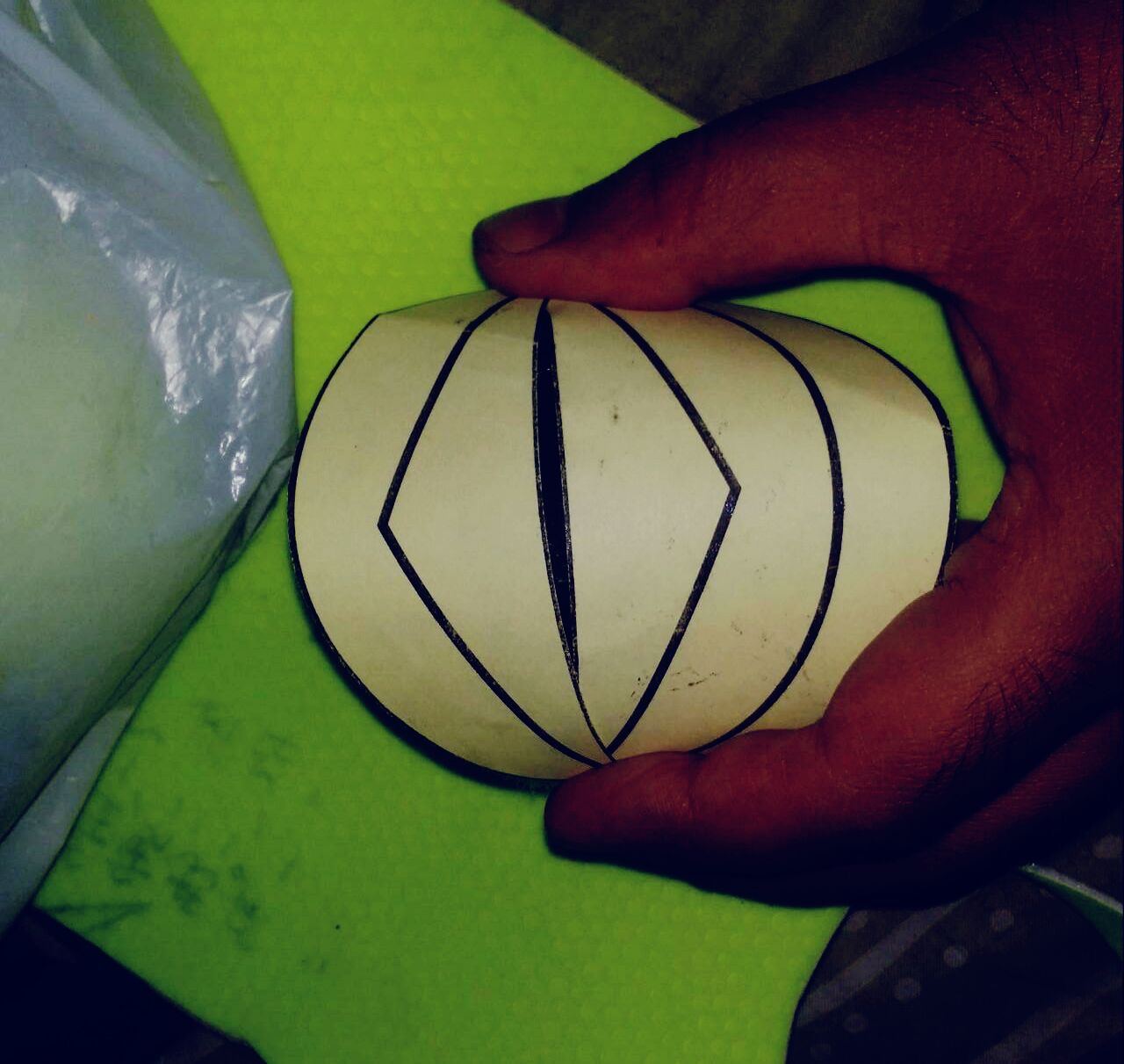 An early paper pattern folded and held by hand into the panelled shape of a sportball