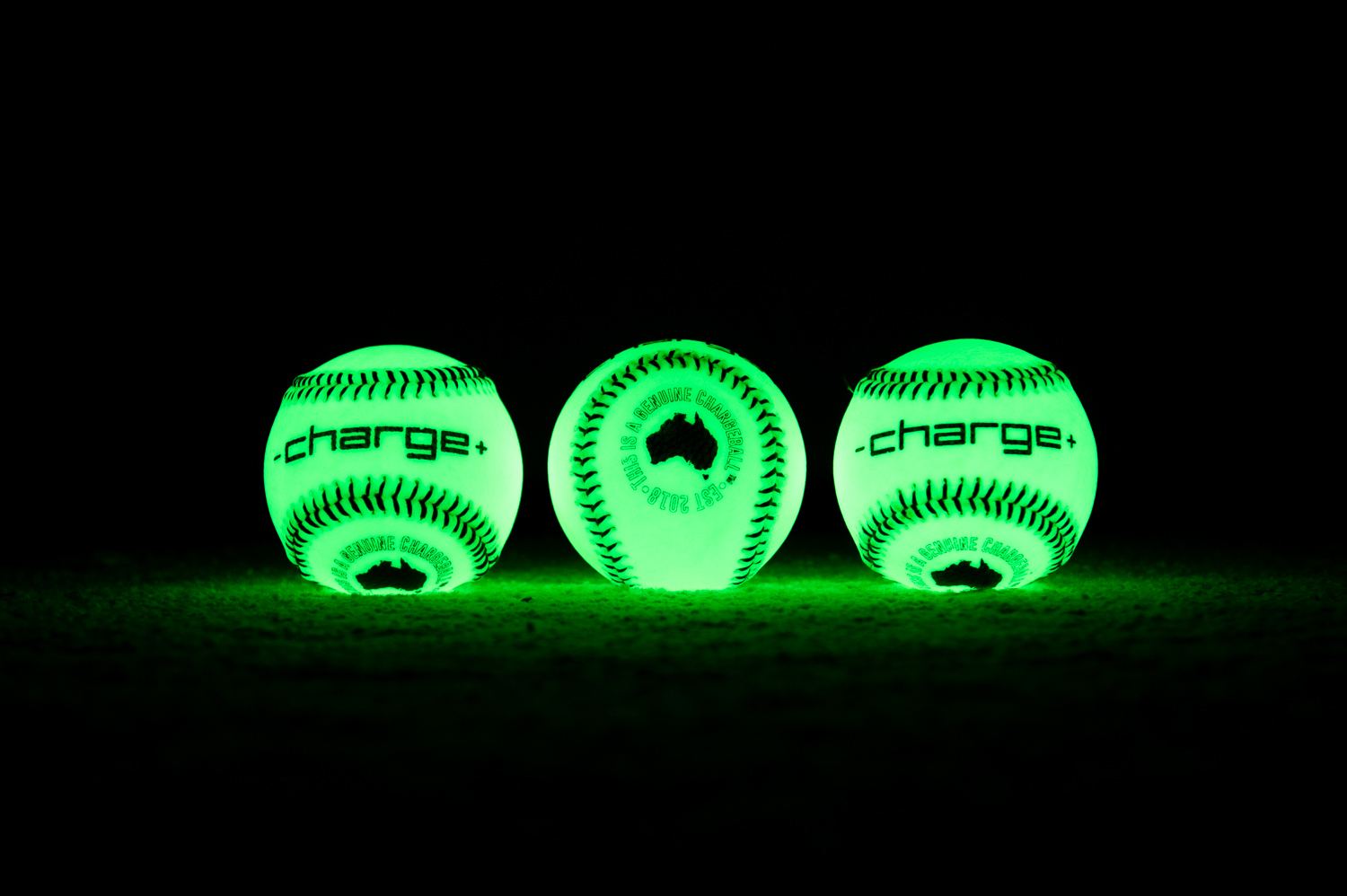 Three glow-in-the-dark Chargeballs lit up against a black background, branded -charge+
